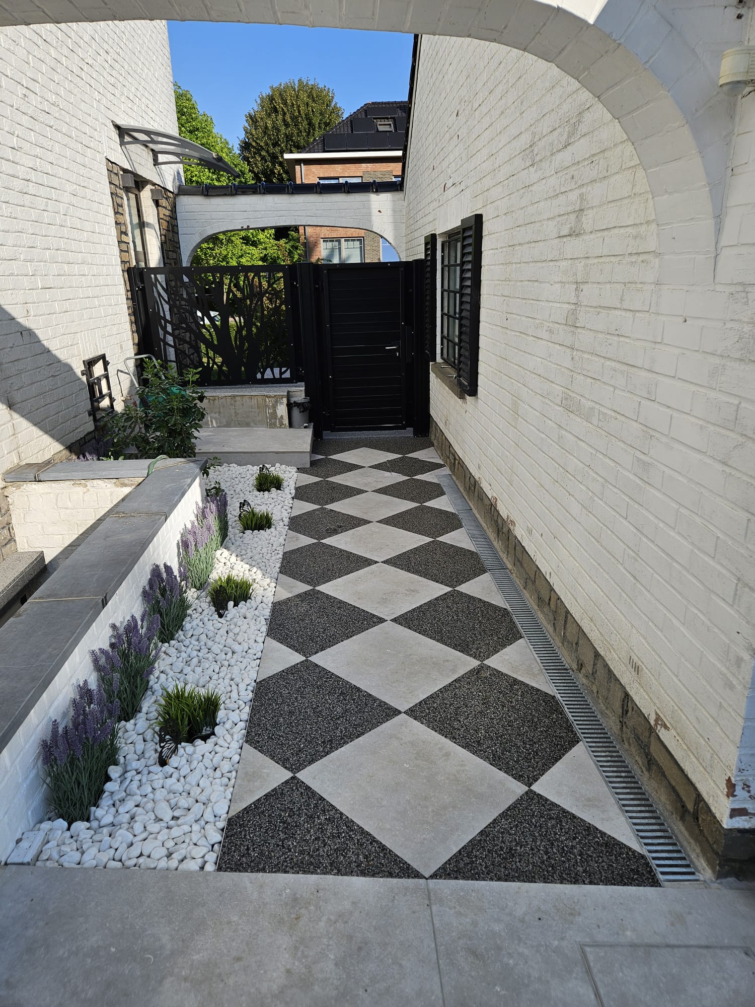 Allée en damier noir et blanc avec massif de galets et lavande