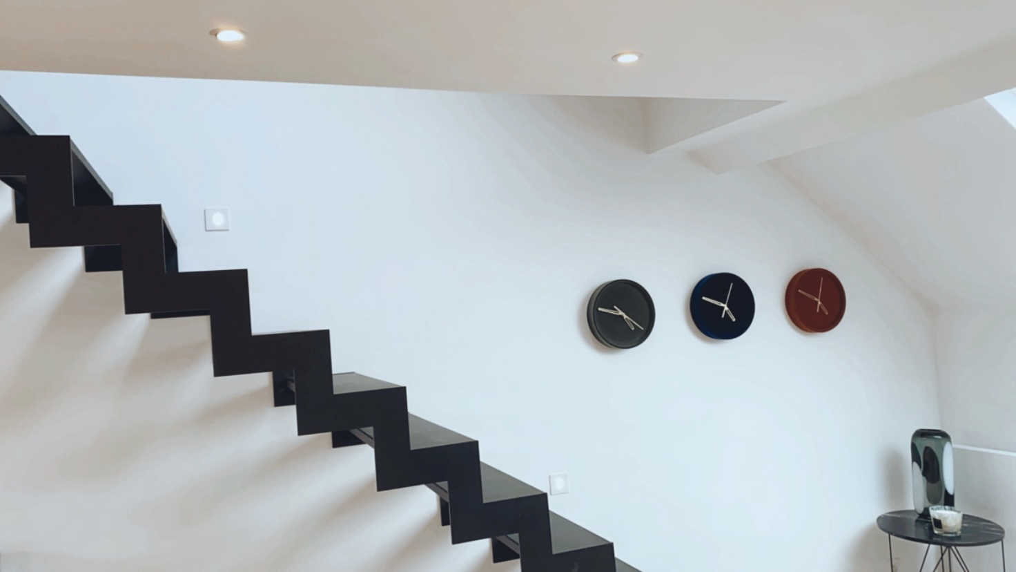 Escalier métallique noir épuré sur mur blanc dans un intérieur minimaliste