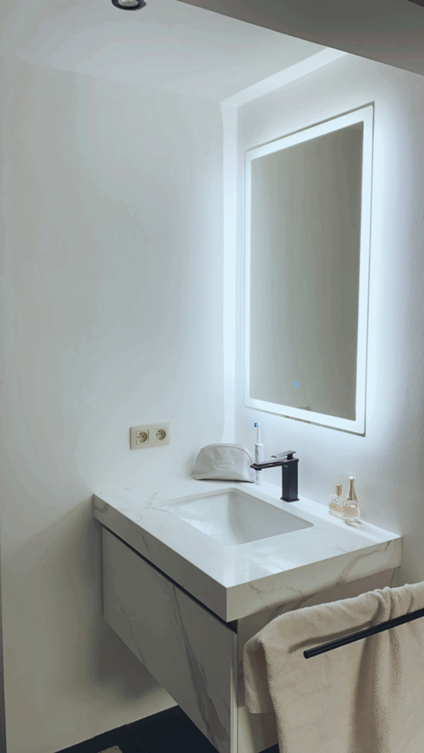 Salle d'eau avec plan en marbre, vasque encastrée et miroir LED rétroéclairé