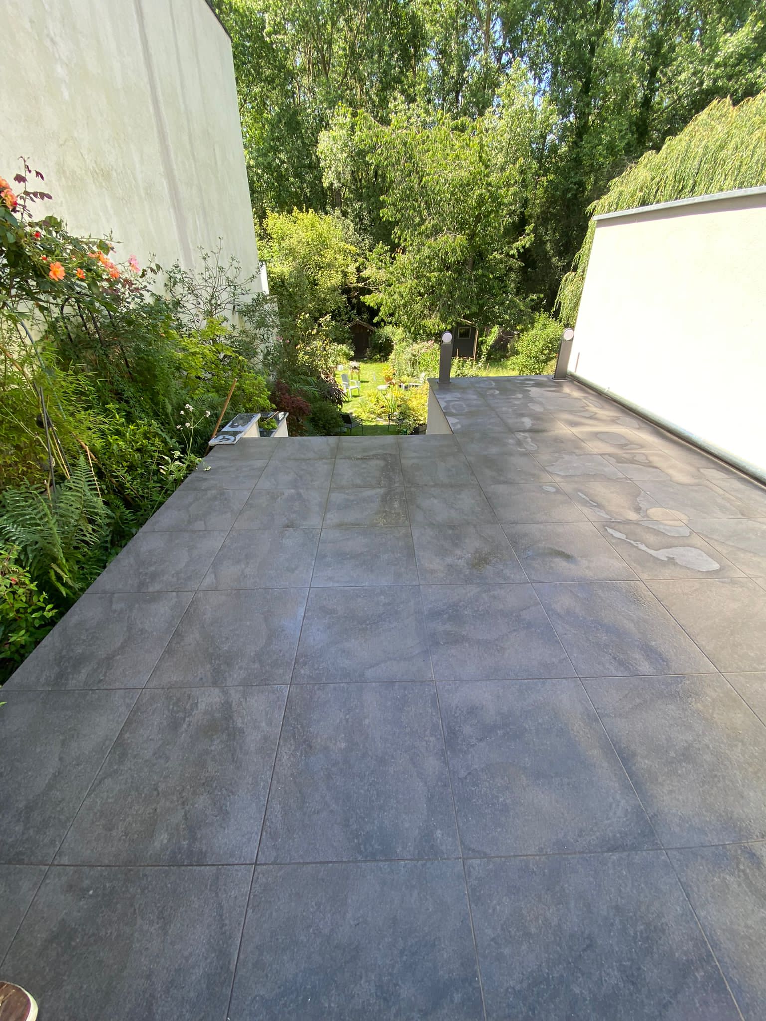 Terrasse en carrelage anthracite grand format avec mur crépi